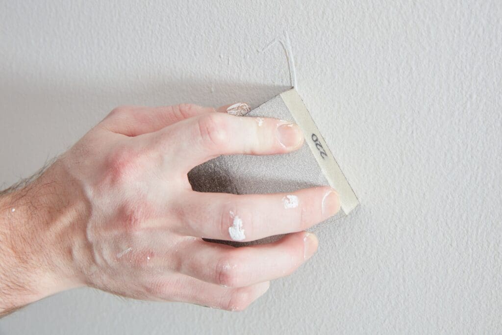 sanding a paint drip from a wall